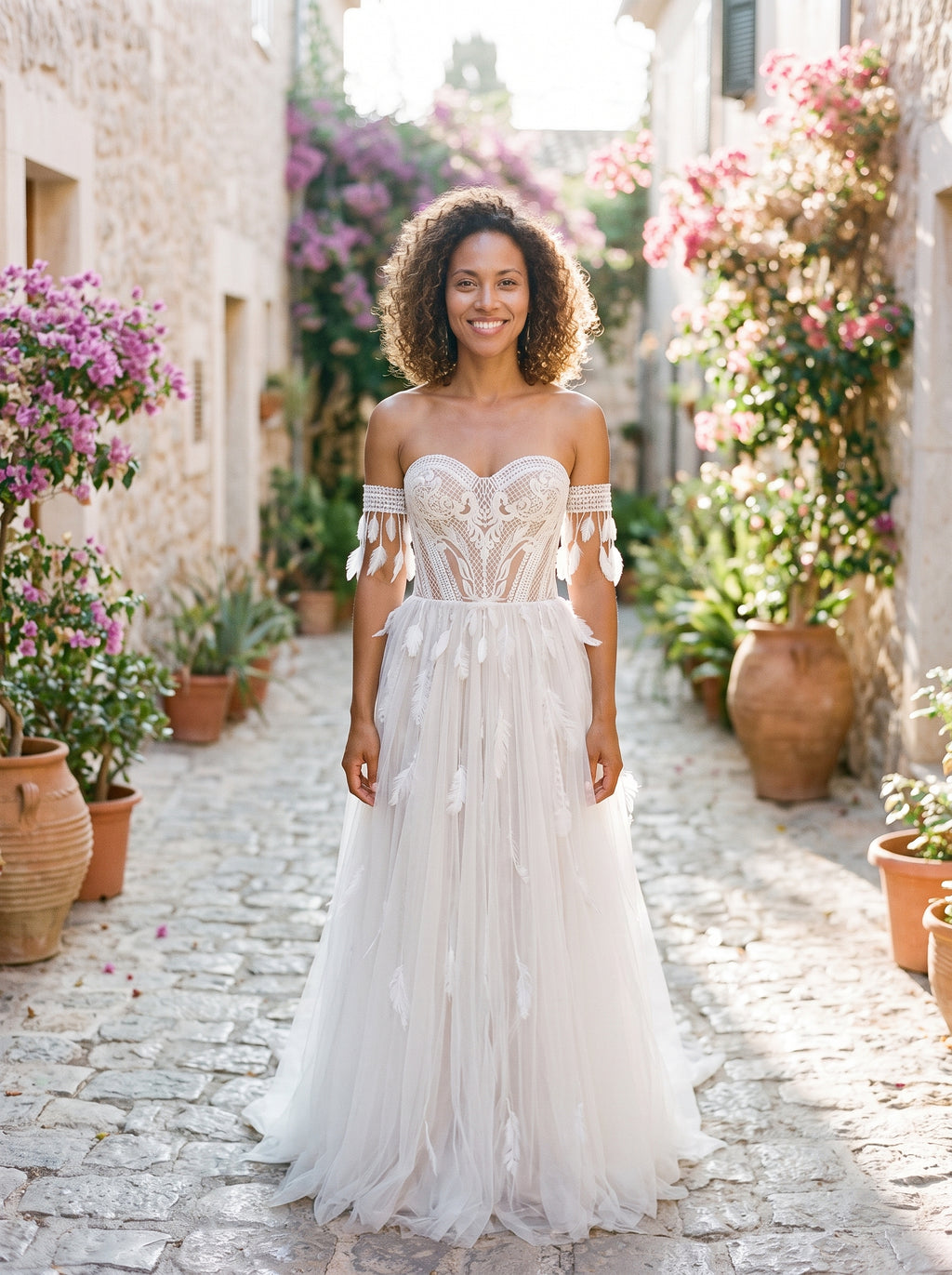 Modèle souriante portant la robe de mariée bohème bustier en dentelle, ruelle méditerranéenne
