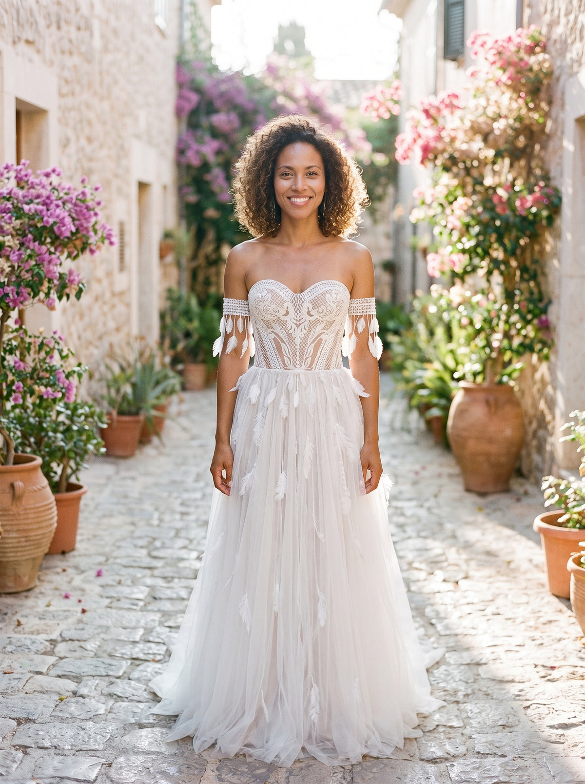 Modèle souriante portant la robe de mariée bohème bustier en dentelle, ruelle méditerranéenne
