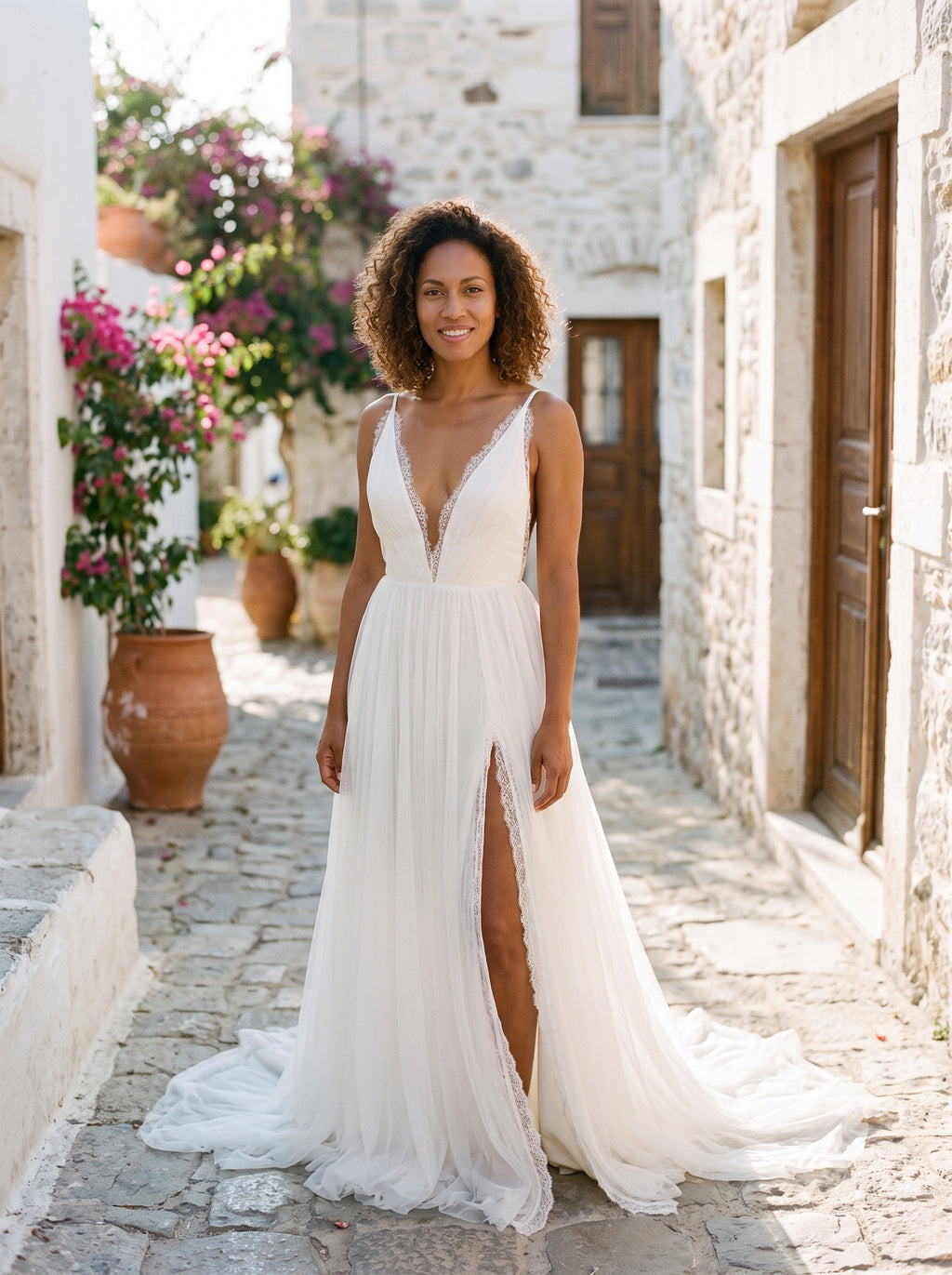 Modèle souriante, robe hippie chic de mariage blanche en mousseline et dentelle, ruelle méditerranéenne
