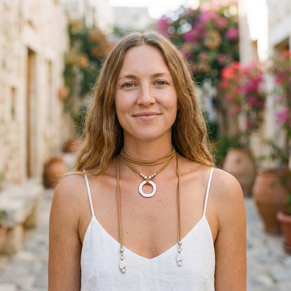 Collier hippie chic à anneau martelé porté par un modèle souriant dans une ruelle