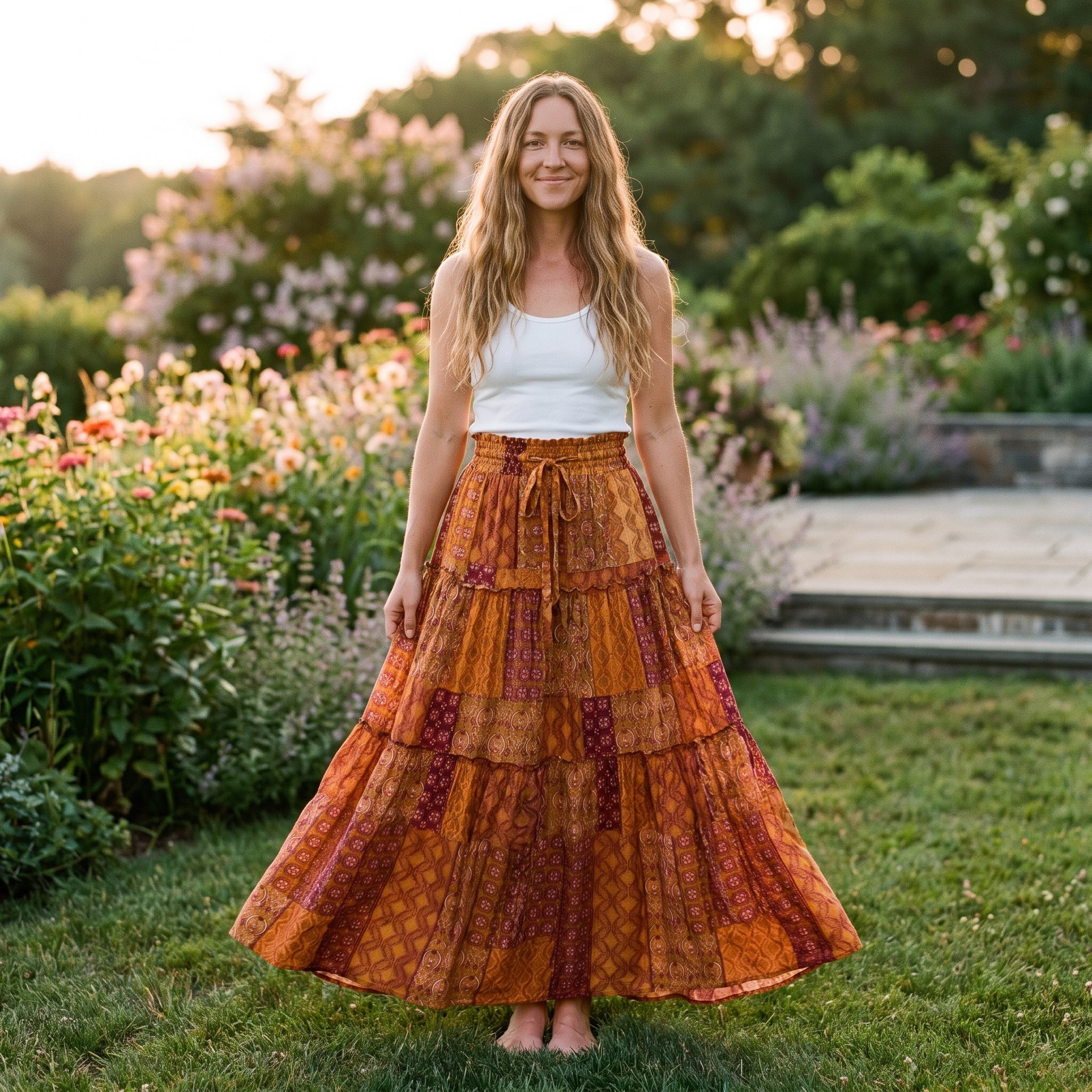 Jupe longue gitane patchwork orange ocre portée par un modèle souriant dans un jardin Bild