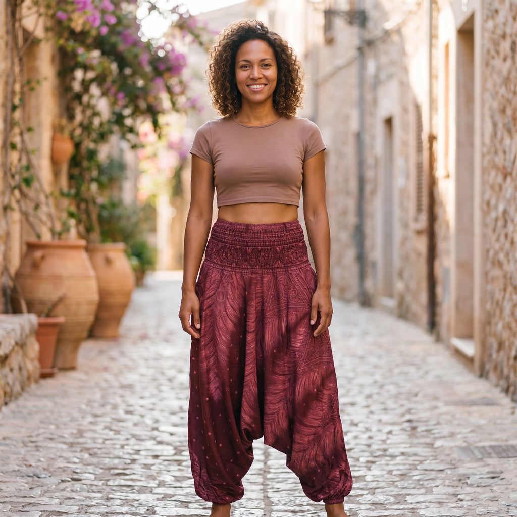 Modèle souriante portant le sarouel femme bordeaux à imprimé plume de paon, ruelle méditerranéenne