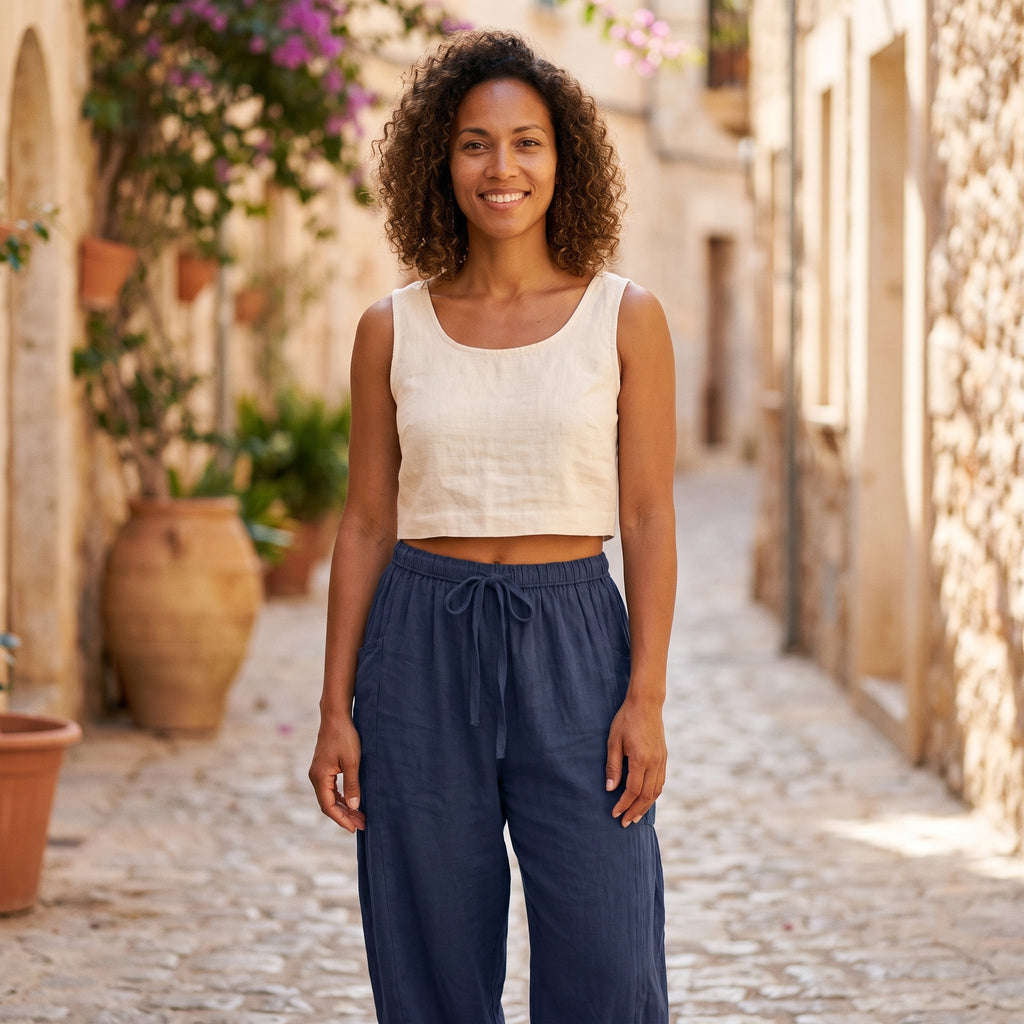 Modèle souriante portant le pantalon sarouel bleu marine ample dans une ruelle méditerranéenne