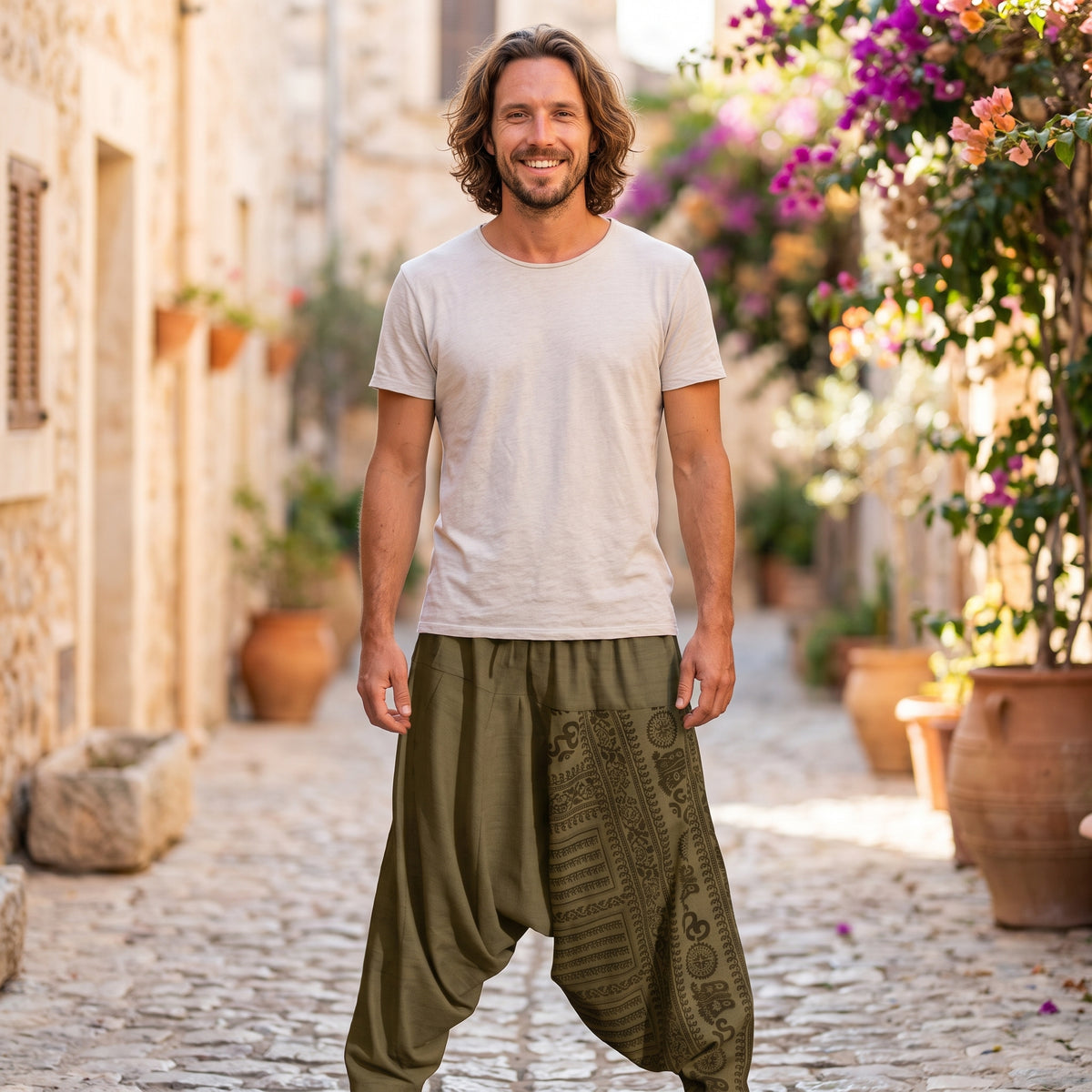 Modèle souriant portant le sarouel homme léger vert à imprimé ethnique, ruelle méditerranéenne