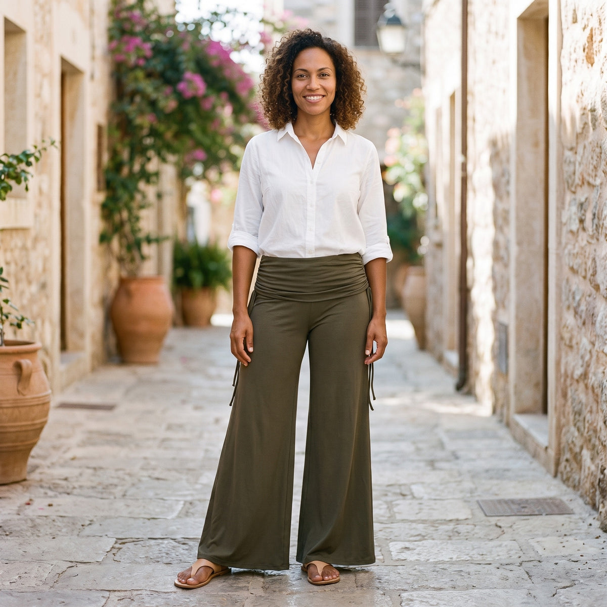 Femme souriante portant le pantalon hippie femme évasé kaki avec une chemise blanche, modèle Style Hippie