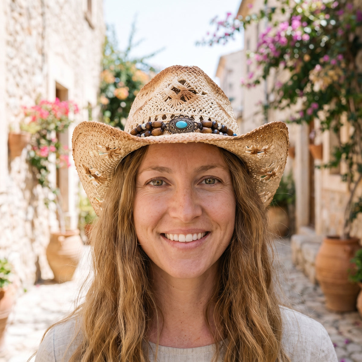Modèle souriante portant le chapeau de paille hippie chic à bandeau de perles et médaillon turquoise, ruelle méditerranéenne Bild