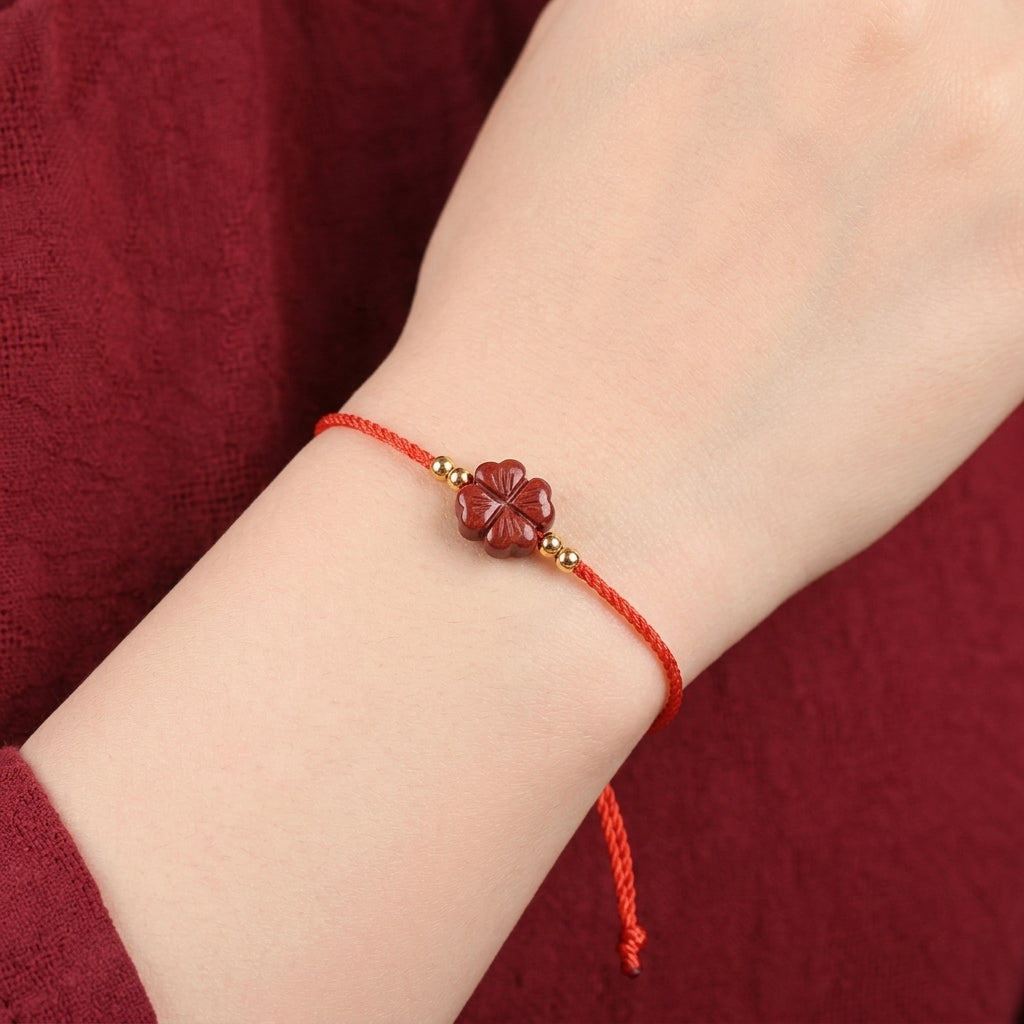 Bracelet cinabre trèfle porté au poignet, cordon rouge